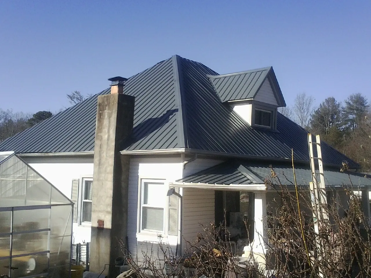 Dark blue standing seam metal roof on a white farmhouse with dormer — Slate & Tile Roof Repair by Roofing Brothers in Shirleysburg