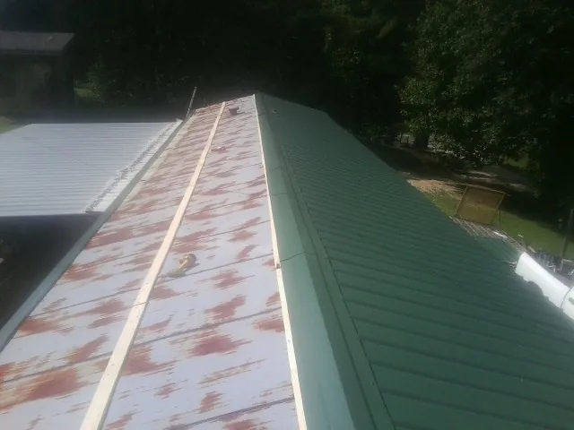 Old rusted panels beside newly installed green metal roofing — Wind Damage Roof Repair by Roofing Brothers in Shirleysburg