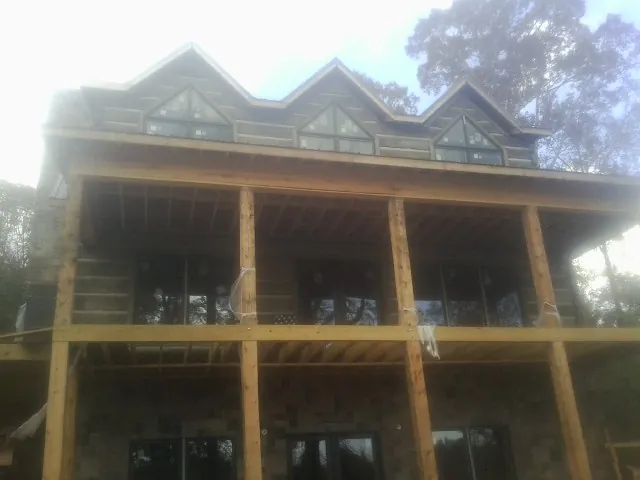 Dormers and porch framing on a large log home under construction — Roof Coating work by our crew in Shirleysburg