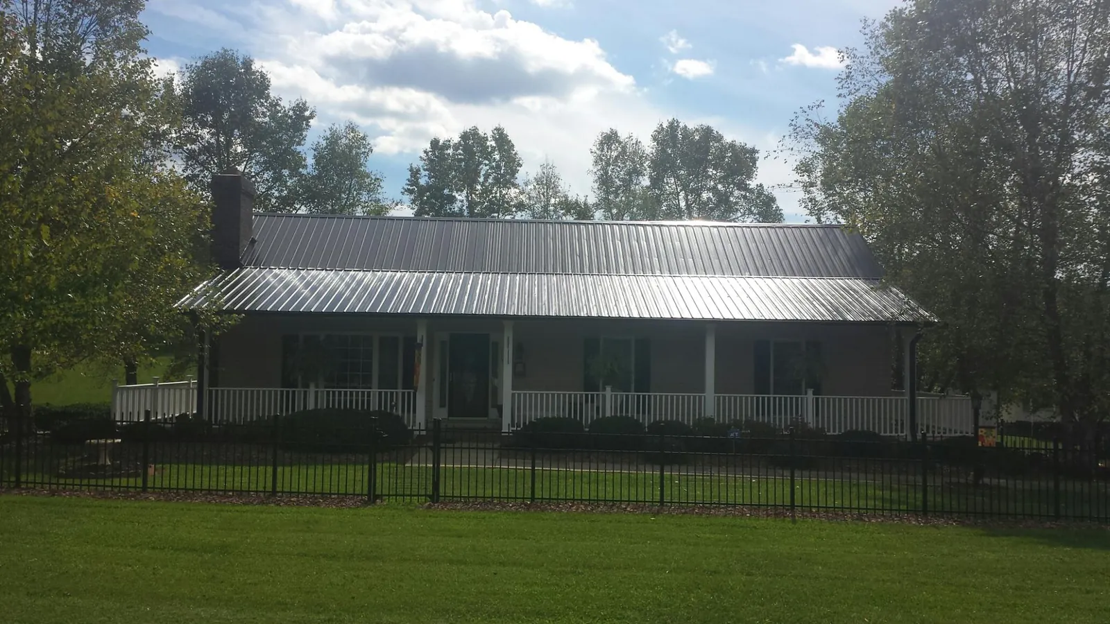 Gray metal roof on a brick ranch with a full width front porch — Gutter Guard Installation work by our crew in Shirleysburg