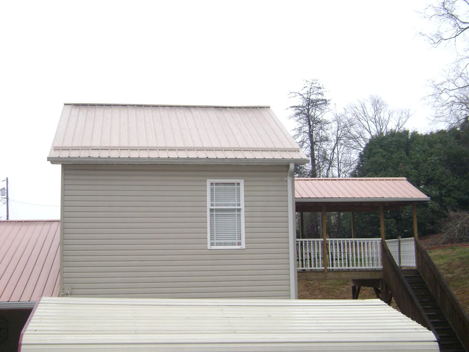Tan metal roofs on a two story addition and attached porch, from a Roof Replacement job in Shirleysburg