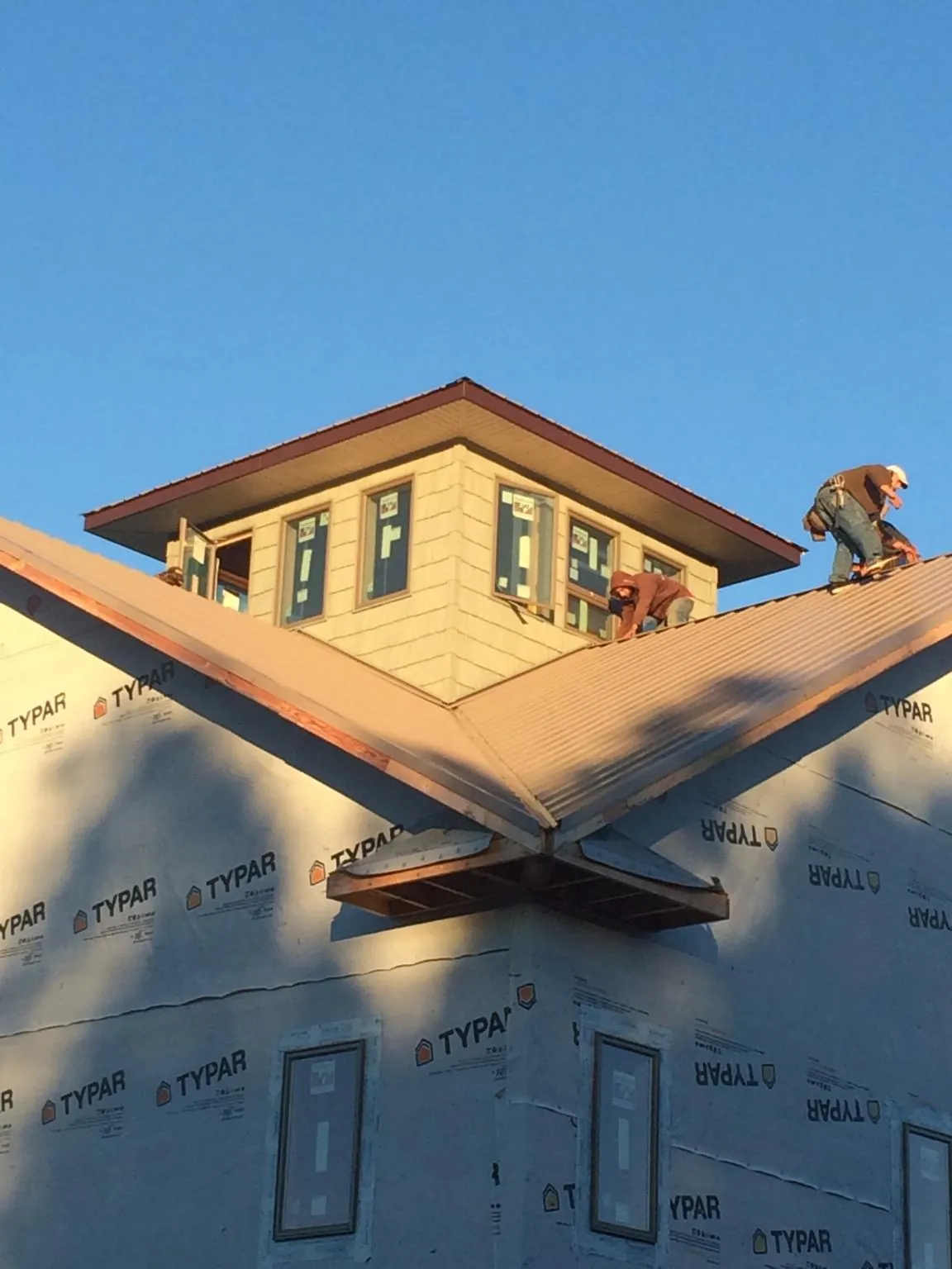 Roofers working around a rooftop cupola on a new metal roof at sunset — Roof Waterproofing in Shirleysburg by Roofing Brothers